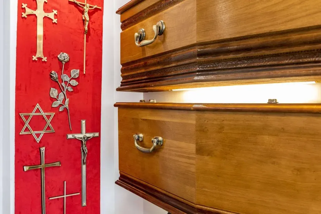 Exposition de cercueils en bois massif avec poignées métalliques dans un showroom funéraire